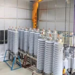 Multiple rows of tall, white, ribbed cylindrical objects stand on metal frames in a room.