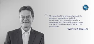 A man in a suit and glasses smiles next to a quote by Wilfried Breuer.