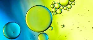 Yellow and blue oil bubbles float in a liquid.