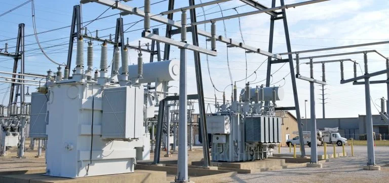 Electrical transformers and power lines stand in an outdoor substation.