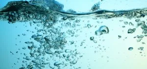 Numerous air bubbles float in clear blue water.