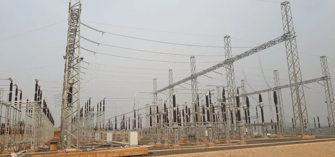 An electrical substation with metal towers and power lines under a gray sky.