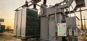 A large gray electrical transformer stands outdoors under a pale sky.