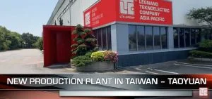 A white industrial building with red accents and large windows.
