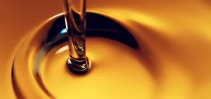 A stream of amber liquid pours into a pool of the same liquid.