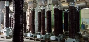 Several tall, dark brown ribbed insulators stand in a row on metal bases.