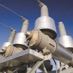Electrical insulators and equipment stand against a clear blue sky.