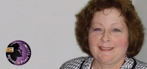 A smiling woman with short brown hair looks toward the camera.