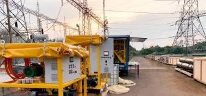 Yellow industrial machinery and equipment sit on a dirt path near power lines.