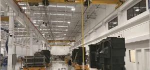 A large, brightly lit industrial warehouse with high ceilings and overhead cranes.