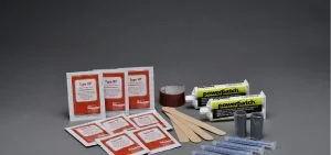 Several white packets with red labels, tubes, and small rolls sit on a gray surface.