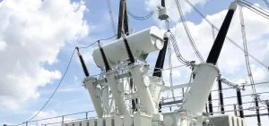 White electrical transformers stand against a cloudy sky.