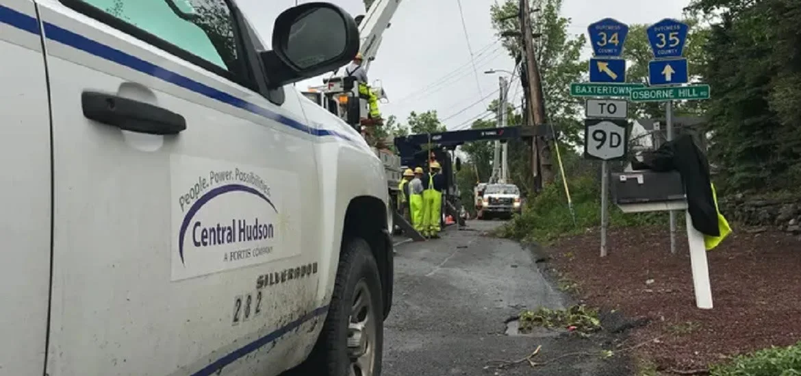 A white utility truck is parked on a road next to road signs and workers.