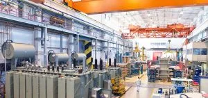 Large electrical transformers sit in an industrial facility.
