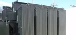 A large, dark green industrial electrical transformer with vertical cooling fins.