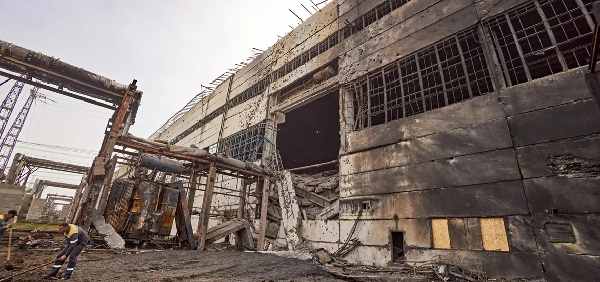 A large, damaged concrete building with charred walls and broken windows.