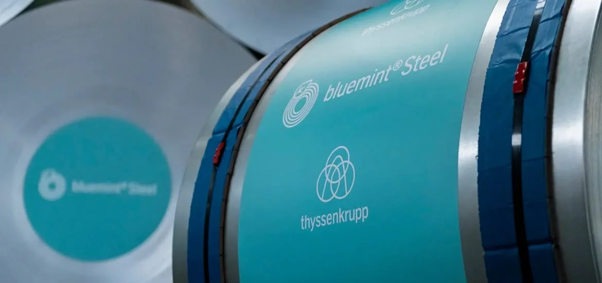 Large rolls of teal-colored steel with white text.