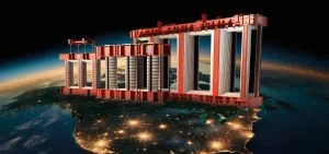 Large red structures stand above a nighttime view of a landmass with city lights.