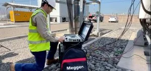 A person in a high-visibility vest kneels next to an open testing device and a black bag.