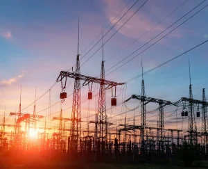 Electrical power lines and transmission towers stand against a sunset sky.