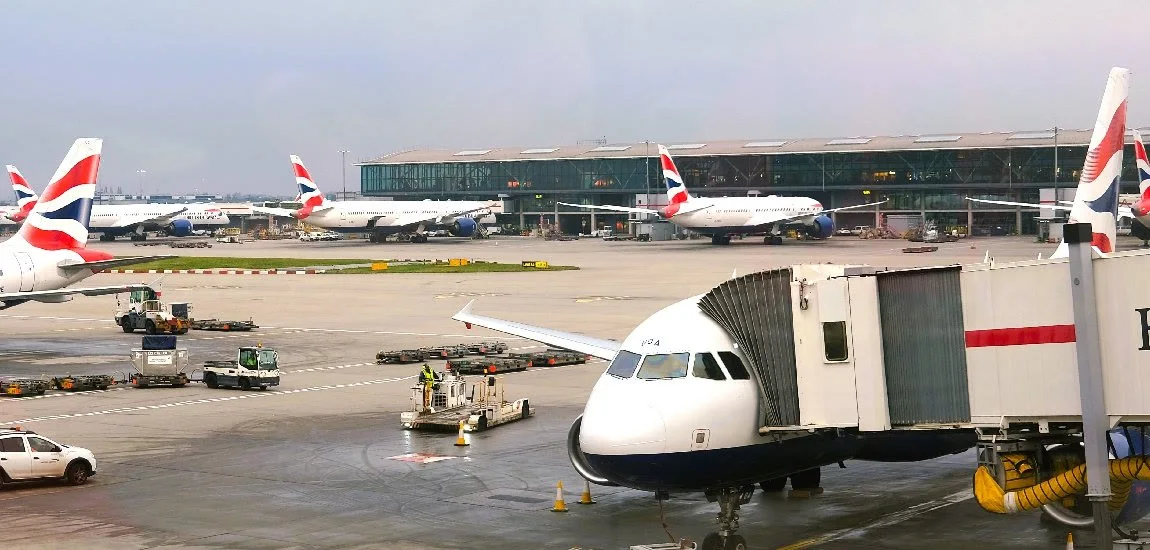 Several airplanes sit on an airport tarmac near a terminal building.