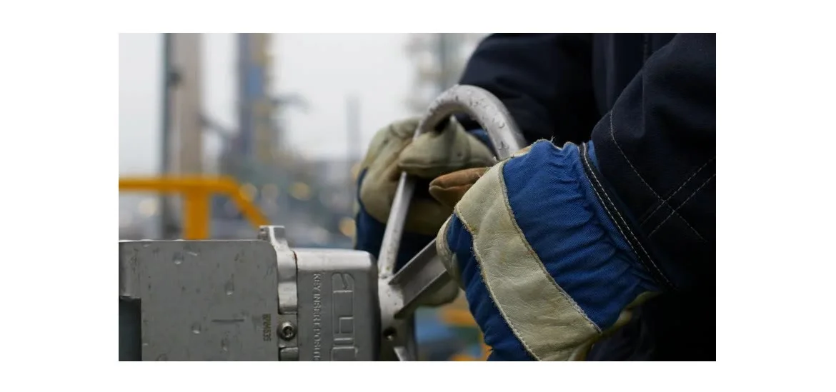 A person wearing gloves holds a metal ring attached to a piece of equipment.