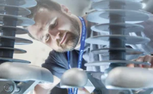 A man looks at large electrical insulators.