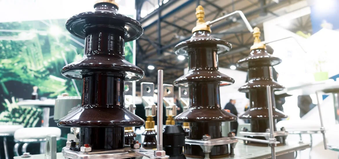 Three dark brown electrical insulators stand in a row on a table.