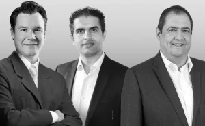 Three men in suits pose for a black and white portrait.