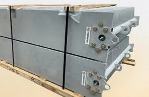 Two large grey metal components sit on a wooden pallet.
