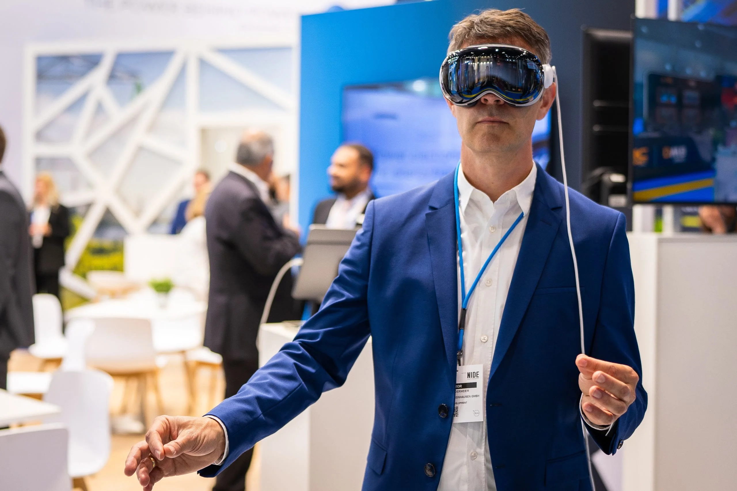 A man in a blue suit wears a virtual reality headset.