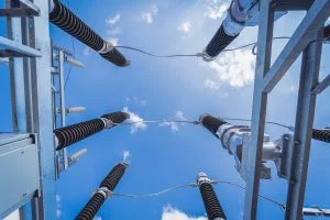 Electrical insulators extend toward a blue sky with white clouds.